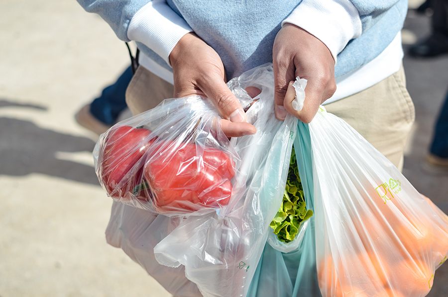 Persona con las manos llenas de bolsas de plástico reciclado del supermercado. 