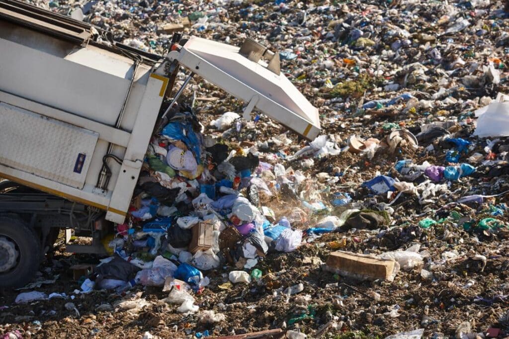 Camión de basura descargando desechos en un vertedero, ilustrando la problemática ambiental que PlasticBag.es aborda con sus bolsas de basura reciclables.