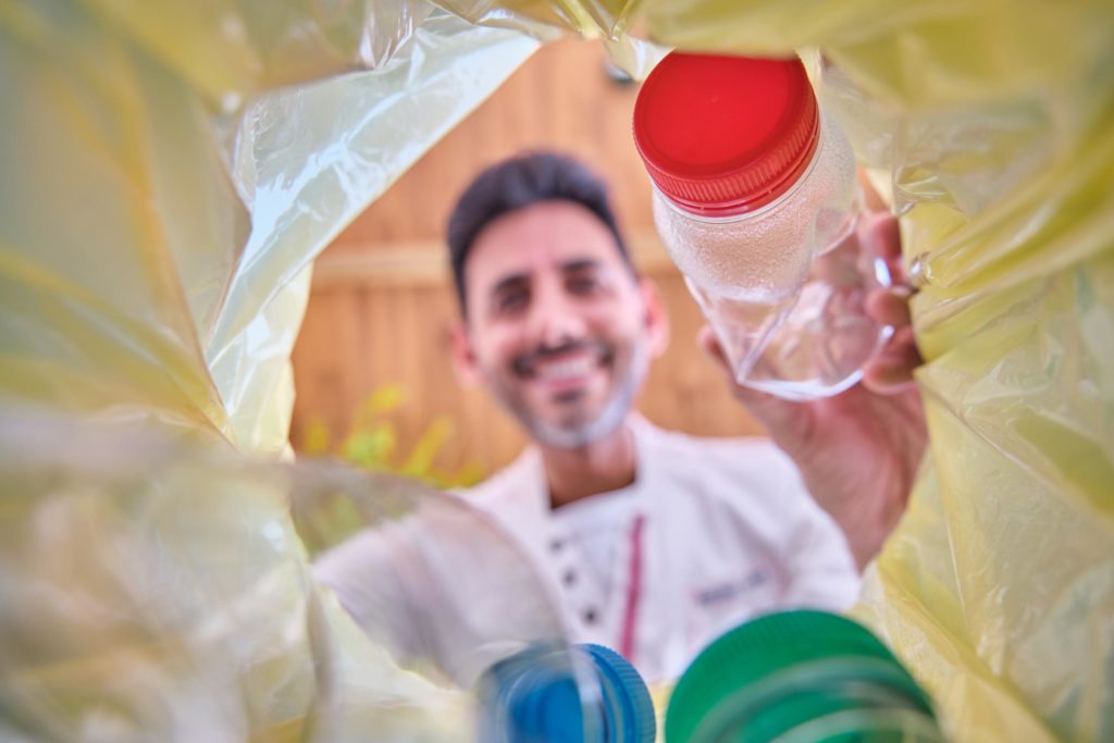 Hombre reciclando una botella de plástico, ilustrando la importancia de la gestión adecuada de residuos según la nueva normativa.